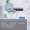 A small white ultrasonic cleaner with an open blue lid sits on a surface next to folded towels. Product specifications are displayed below. Produktbild-Vorschau