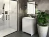 A modern bathroom scene featuring a white vanity cabinet with a sink and mirror, next to a glass-enclosed shower and a potted plant. Produktbild-Vorschau