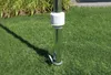 A close-up shot of a metal pole anchored in the grass, with a white plastic adjustment collar. Podgląd zdjęcia produktu