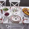 A festive Christmas table setting with plates, cutlery, food, and a candle. Produktbild-Vorschau