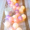 A string of colorful LED ball lights and a candle are arranged on a textured runner. Náhled obrázku produktu