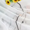 A close-up view of a sheer white curtain with a gray embroidered wave pattern and sunflowers. Produktbild-Vorschau