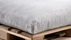 A close-up of a gray corduroy cushion placed on a wooden pallet. Produktbild-Vorschau