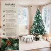 A decorated Christmas tree in a cozy living room setting with a chair and ottoman. Produktbild-Vorschau