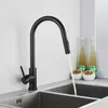 A black kitchen faucet with water running into a double sink. Produktbild-Vorschau