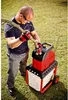 A man is using a garden shredder to shred a branch outdoors on a grassy lawn. Produktbild-Vorschau