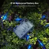 A close-up of a battery-operated LED string light set with blue lights, resting on green foliage, with water droplets on the battery box. Produktbild-Vorschau
