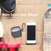 A flat lay of items for sports and travel, including shoes, headphones, a phone, dumbbells, and a water bottle, arranged on a wooden surface. Produktbild-Vorschau