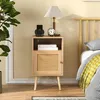 A bedside table with a lamp, clock, and phone charger next to a bed. Produktbild-Vorschau
