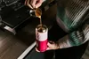 A person pouring coffee into a pink and light pink insulated tumbler. Náhled obrázku produktu