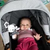 A baby lying in a stroller with a toy. Anteprima dell’immagine prodotto