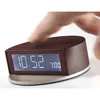 A hand is pressing the top of a brown digital alarm clock. The clock displays the time 10:52 and an alarm time of 7:00. Produktbild-Vorschau