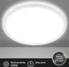 A white, round LED ceiling light with a backlight effect, mounted on a light gray ceiling. Produktbild-Vorschau