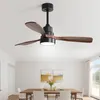 A modern ceiling fan with wooden blades and an integrated light fixture is shown in a dining room setting. Produktbild-Vorschau