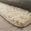 A close-up view of a fluffy cream-colored rug with a gray backing partially visible. Produktbild-Vorschau