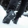 Close-up of a person's feet wearing winter boots with spikes in the snow. Podgląd zdjęcia produktu