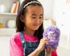 A young girl is holding a purple plush hedgehog toy. Náhled obrázku produktu