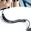 A coiled black USB-C cable on a white surface, with a person's hands holding a phone in the background. Anteprima dell’immagine prodotto
