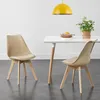 Two beige dining chairs with wooden legs are placed around a white table, with a yellow pendant light hanging above. Náhled obrázku produktu