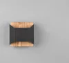 A modern wall light with a square black metal insert and a wooden frame, set against a plain gray background. Podgląd zdjęcia produktu