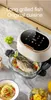 A kitchen appliance with a grilled fish inside, alongside dishes of pasta and fruit. Produktbild-Vorschau