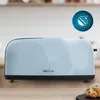 A light blue toaster is shown on a wooden countertop with a blurred kitchen background. A circular blue icon with white symbols is in the top right corner. Voir les images du produit