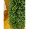 A close-up view of a green artificial Christmas tree with wooden flooring and a wooden wall in the background. Podgląd zdjęcia produktu