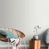 A cozy corner of a room with a wicker chair, a blanket, and a small wooden table with a vase and decorative branches. Produktbild-Vorschau