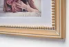 A close-up of a beige wooden picture frame with a beaded detail, holding a photo of a mother and child. Podgląd zdjęcia produktu
