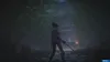 A person holding a sword in a dark, wooded area with a building in the background. Náhľad obrázku produktu