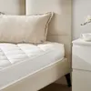 A close-up view of a mattress and pillow on a bed, with a nightstand in the background. Anteprima dell’immagine prodotto