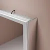 A close-up view of the corner of a silver framed mirror cabinet with a glass shelf and a black cable attached to the top. Náhled obrázku produktu
