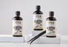 Three bottles of vanilla extract are displayed on white pedestals, with vanilla beans in the foreground. Produktbild-Vorschau
