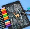 A black notebook with a nature-themed drawing of a deer and trees, surrounded by colorful acrylic paint markers. Náhľad obrázku produktu