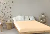 A bedroom scene with a bed, pillows, and a side table. Produktbild-Vorschau
