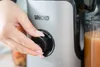 Eine Hand mit manikürten Nägeln dreht den Regler am silbernen Unold Slow Juicer Sam von AUS auf EIN, Produktbild-Vorschau