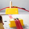 Zwei Bilder einer roten Spielzeugauto-Strecke mit gelben Behältern, mit Spielzeugautos auf den Strecken und einem Kind, das zuschaut Anteprima dell’immagine prodotto