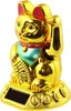 A golden lucky cat figurine with a red collar and green bib, sitting on a golden base with a solar panel. Produktbild-Vorschau