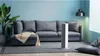 A modern living room with a sofa, rug, plant, and a white heater. Voir les images du produit