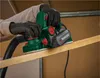 A person wearing gloves is using a green electric planer on a wooden plank. Produktbild-Vorschau