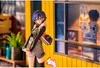 A figurine of a character standing in front of a yellow building with a window display. Produktbild-Vorschau