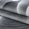 A close-up view of a folded carpet with an abstract pattern. Produktbild-Vorschau