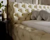 A close-up view of a tufted beige upholstered bed frame and pillows. Náhľad obrázku produktu
