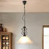 A pendant light hangs from the ceiling above a wooden cabinet filled with decorative items. Produktbild-Vorschau