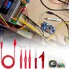 A collection of electronic testing tools and components, including multimeter test leads, alligator clips, and a voltage regulator module, arranged on a surface. Produktbild-Vorschau