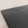 A close-up, angled view of a black shower tray with a textured surface, placed on a light wooden floor. Produktbild-Vorschau