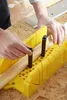 Hands using a yellow miter box to cut a piece of wood. Náhľad obrázku produktu