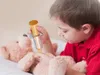 A young boy is playing doctor with a teddy bear, using a toy syringe. Voir les images du produit