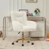 A white fluffy office chair with gold legs is placed in front of a desk with a laptop and flowers. Produktbild-Vorschau