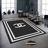 A modern living room with a black and white rug featuring a prominent logo. Produktbild-Vorschau